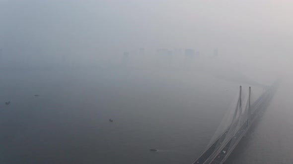 Dolly back drone shot of Mahim bay Mumbai sealink bridge on a hazy polluted day alt