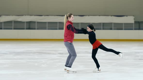 Figure skating coach showing the right position of hands to girl