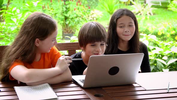 Children, boy and girl, using laptop computer for online learning in garden at home