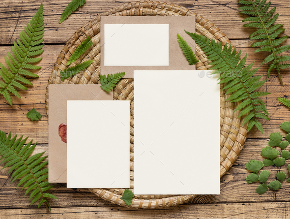 Wedding cards and envelope on wooden table with fern leaves