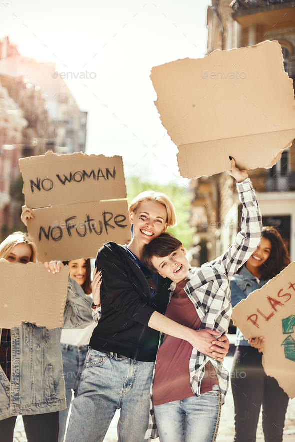 The future is female. Two happy young women are holding signboards and smiling while standing on the