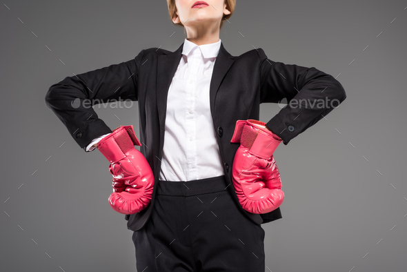 cropped view of strong businesswoman posing in suit and pink boxing gloves, isolated on grey