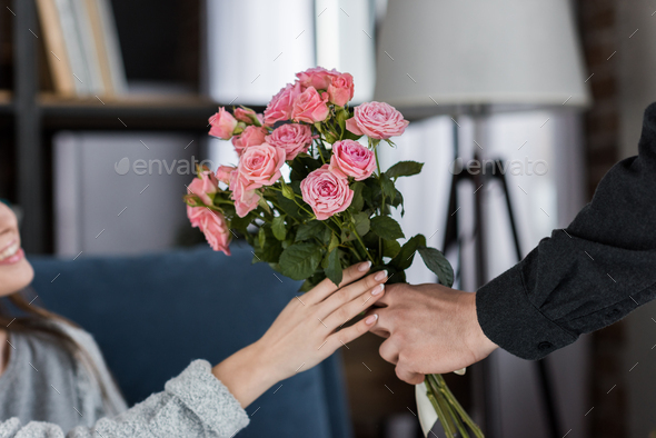 cropped image of boyfriend presenting bouquet of roses to girlfriend on international womens day
