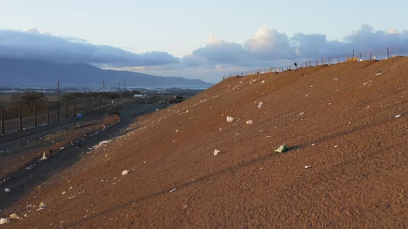 Close Up Remaining Plastic Waste Flying with Wind By Landfill Slope at Sunset alt