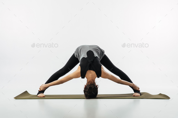 woman practicing yoga and doing wide legged forward fold