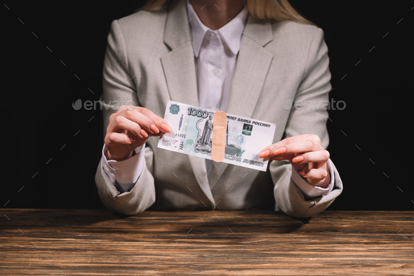 cropped shot of businesswoman holding russian rubles banknote with medical patch