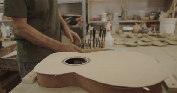 Luthier placing tools by a guitar mold