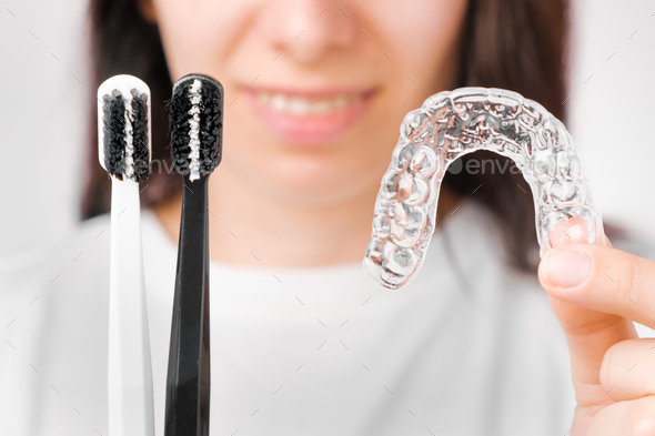 Black and white toothbrushes and invisible removable braces or aligner in woman hands - Stock Photo - Images