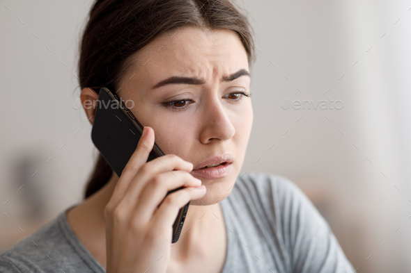 Portrait of sad worried millennial female talking on phone receiving bad news