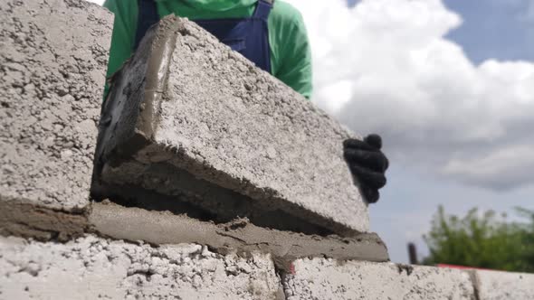 Bricklayer Puts the Brick. Mason Installation of Concrete Blocks. Builder Laying Wall of Building