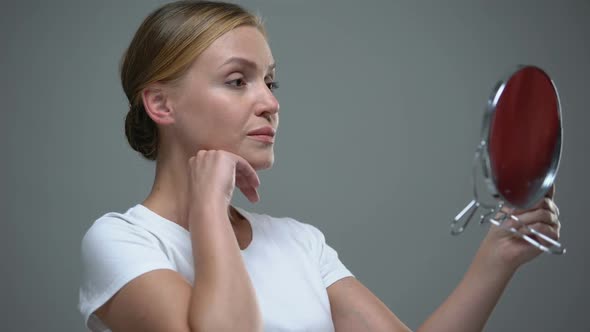 Concerned Woman Looking at Her Reflection in Mirror, Aging Process of Skin