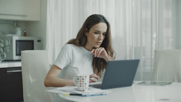 Happy Woman Working Laptop Computer at Home. Excited Woman Reading Good News alt