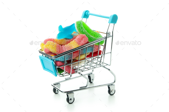 Shop trolley with gummy candies on white background