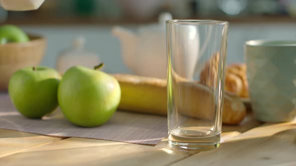 Pouring Milk Into the Glass on Breakfast Table alt