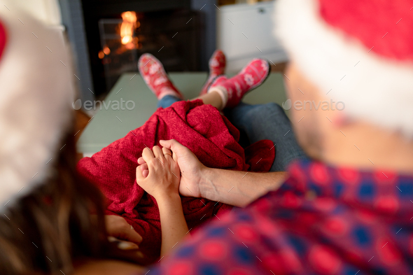 Back view of caucasian couple wearing santa hats and christmas socks at christmas time - Stock Photo - Images
