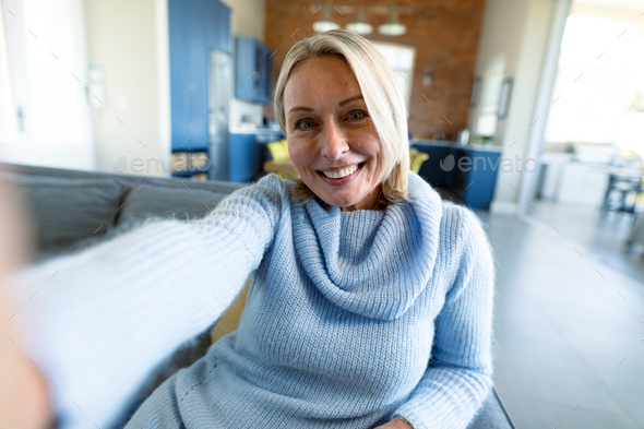 Happy senior caucasian woman in living room sitting on sofa, making video call - Stock Photo - Images
