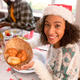 Smiling african american woman wearing santa hat holding basket with rolls - PhotoDune Item for Sale