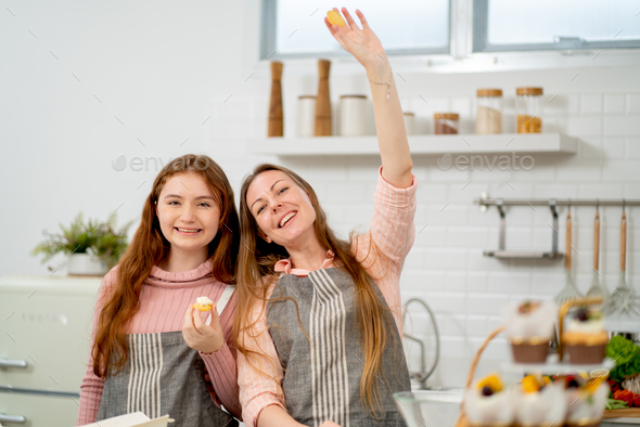 Caucasian mother wave hand and stay with her daughter girl in kitchen