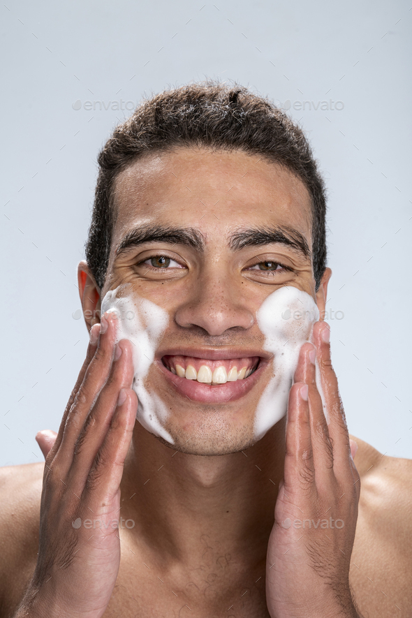 Cheerful man washing his face in the morning