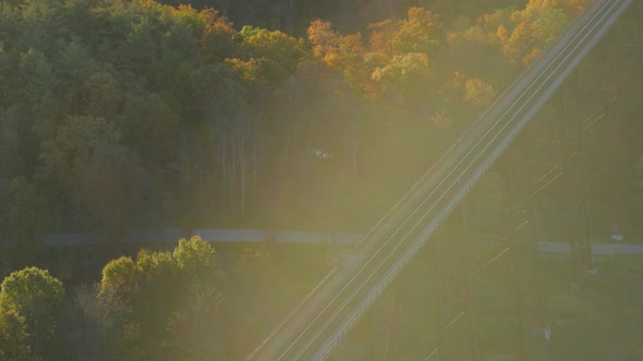 Aerial of railroad bridge passing over autumn forest in valley alt