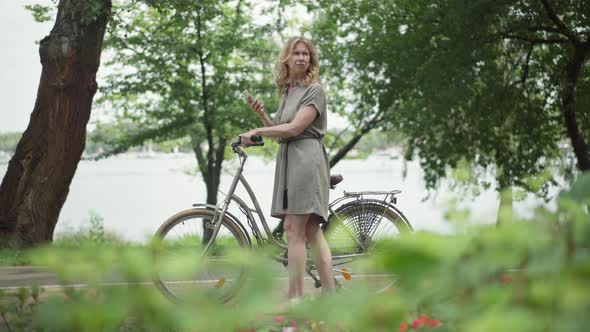 Wide Shot Side View of Happy Middle Aged Female Tourist Checking Online Map in Smartphone Standing alt