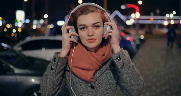 Beautiful Woman Puts Headphones on His Ears in the Night City