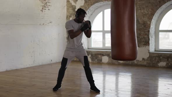 Afro American Boxer Punching the Heavy Bag in the Gym Actively alt
