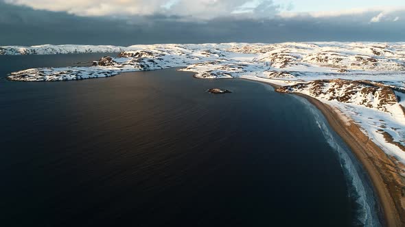 The Coast of the Arctic Ocean Covered with Snow in the Rays of the Setting Sun a Storm is