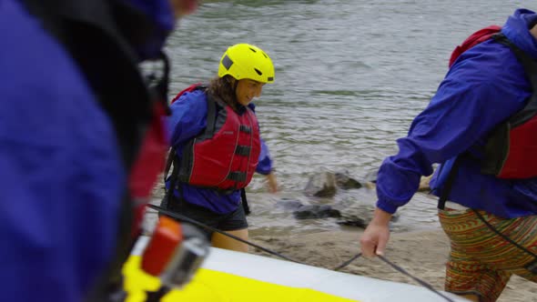 Group of people white water rafting carry raft together