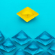 Yellow Paper Ship Out Of The Crowd Concept Over Blue Background - PhotoDune Item for Sale