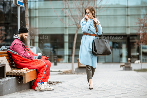 Homeless beggar with passing by business woman