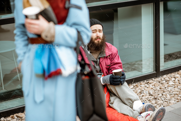 Homeless begging money to a passing by woman