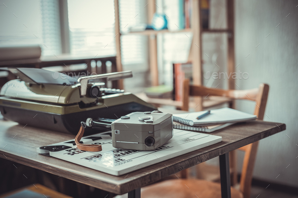 Vintage old film camera and typewriter at wooden desk table