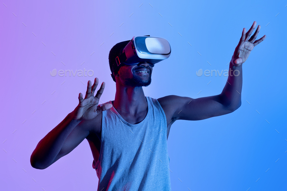 Sporty black athlete wearing VR headset, having virtual training in augmented reality, neon lighting