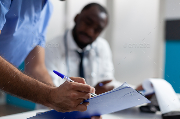 Closeup of physician man nurse checking ill symptoms on clipboard
