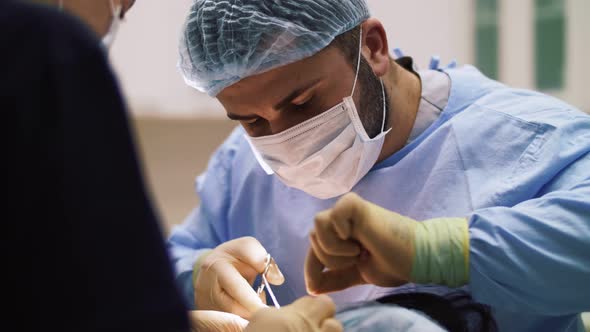 a man surgeon performs face and hands surgery close-up alt