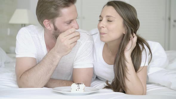 Young Couple Eating Pie in Bed