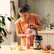 Woman in orange dress pouring fresh milk into electric blender Stock Photo  by Pressmaster