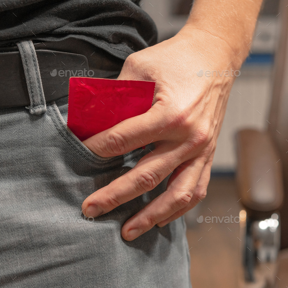 Man pulls a condom out of his jeans pocket