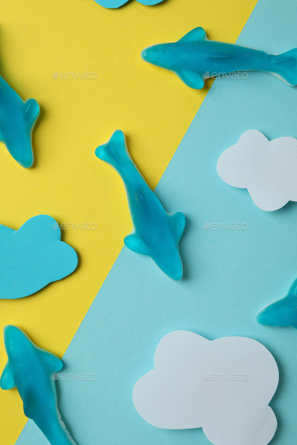 Gummy candies in the form of whale and decorative clouds on two tone background