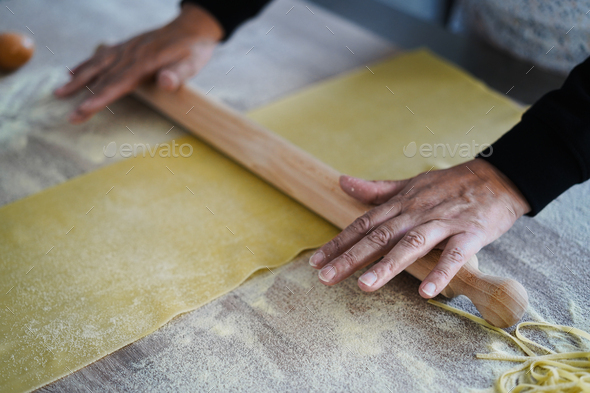 Woman preparing dough for tagliatelle inside pasta factory