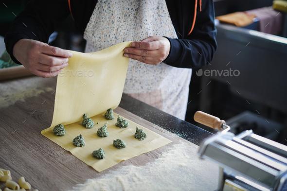 Woman prepare fresh made ravioli inside pasta factory