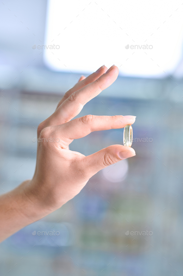 Pharmacist demonstrating a capsuleshaped tablet before the camera