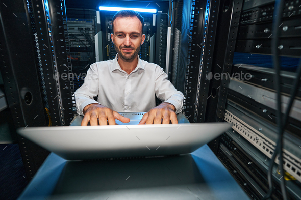 Satisfied data center manager checking network settings with laptop