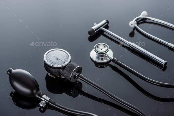 close up view of device for measuring pressure, reflex hammer and stethoscope on glass surface