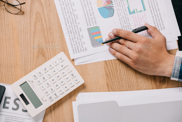 cropped shot of businessman at workplace with papers and calculator - Stock Photo - Images