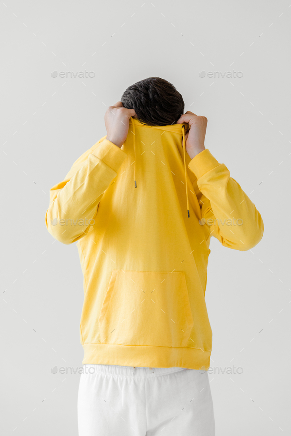 young man taking off yellow hoodie isolated on white - Stock Photo - Images