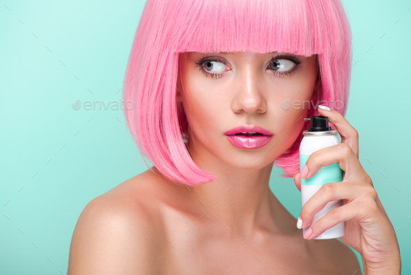attractive young woman with pink bob cut holding coloring hair spray isolated on turquoise