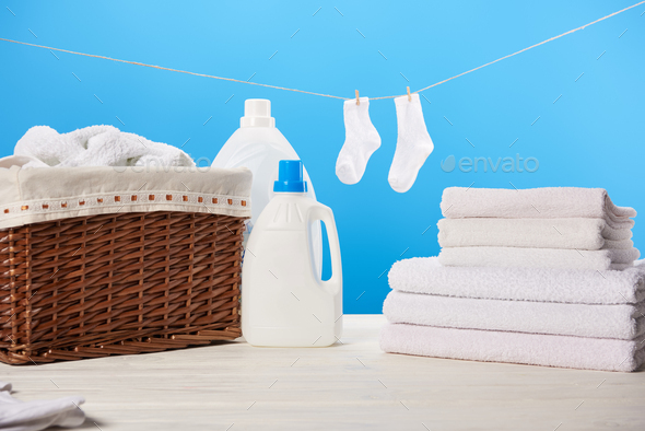 laundry basket, plastic containers with laundry liquids, pile of clean soft towels and white socks