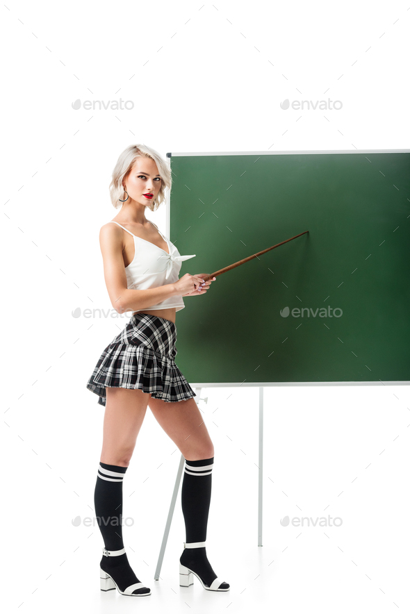 young sexy woman in school skirt and knee socks pointing at empty chalkboard with pointer isolated